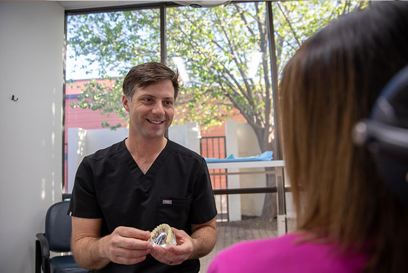 Doctor going over dental procedure information with patient with showing implant model