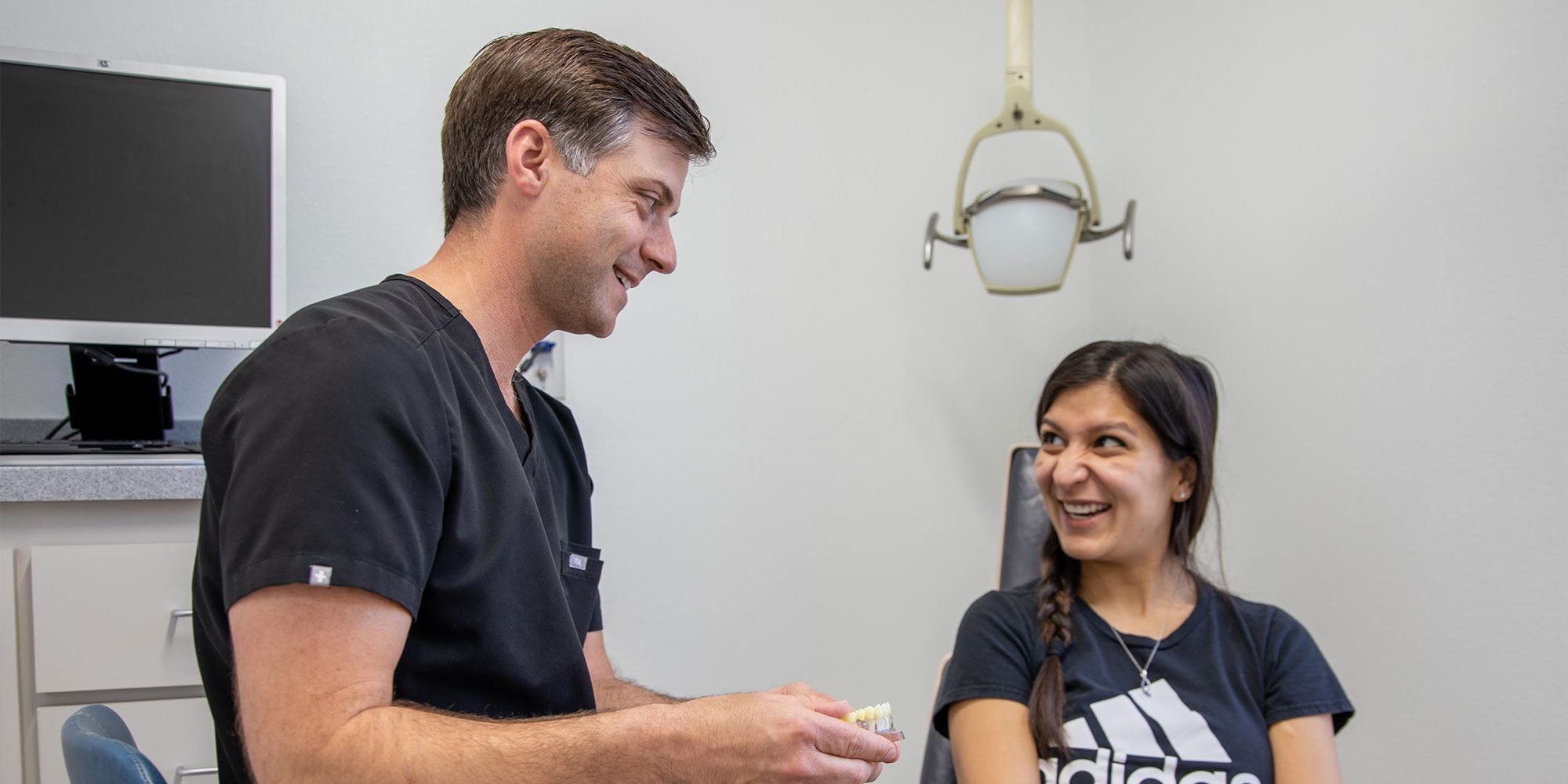 Doctor going over dental procedure with patient and showing implant model