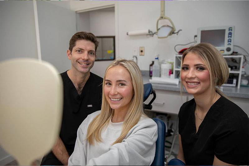 Patient and doctor and staff member smiling after patient dental procedure